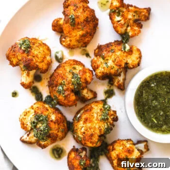 Crispy air fryer cauliflower on a white plate with chimichurri sauce ont top