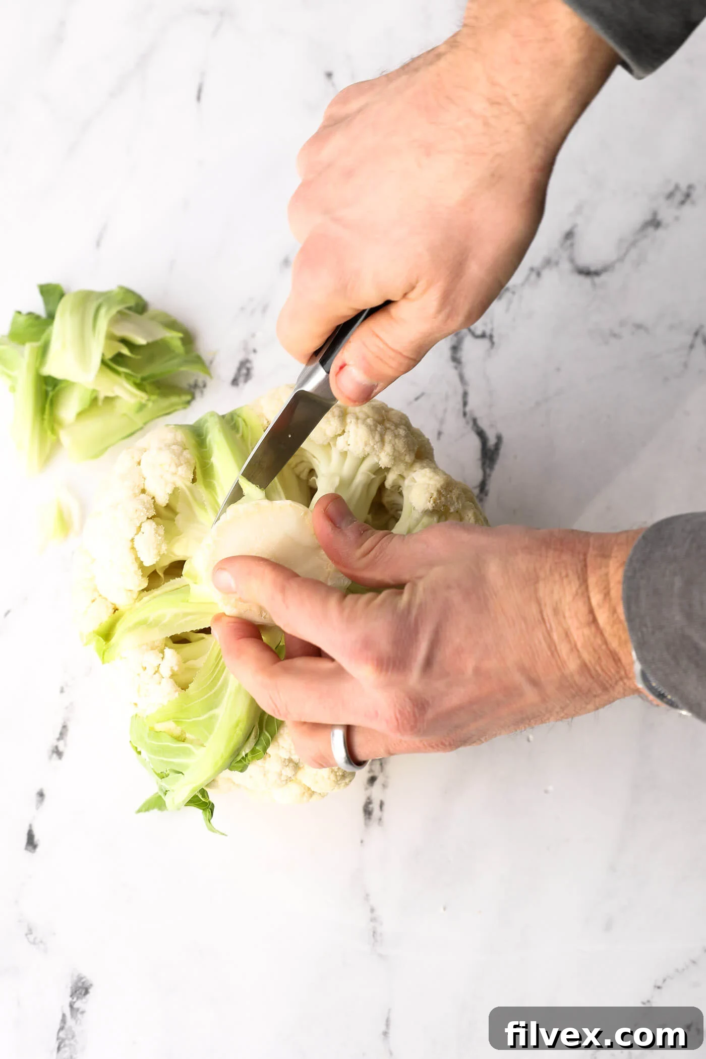 Cauliflower head placed upside down on a cutting board, ready for leaf removal.