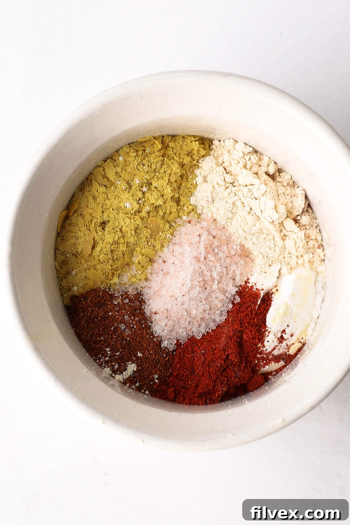 A small bowl containing a mixture of various spices for seasoning cauliflower.