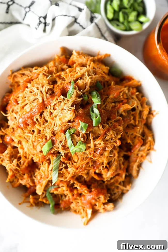 Instant pot buffalo chicken shredded in a bowl with sliced green onions on top
