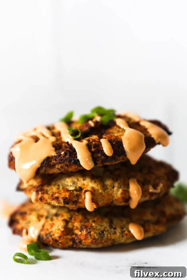 Stack of 3 air fryer salmon patties with sauce on top dripping down