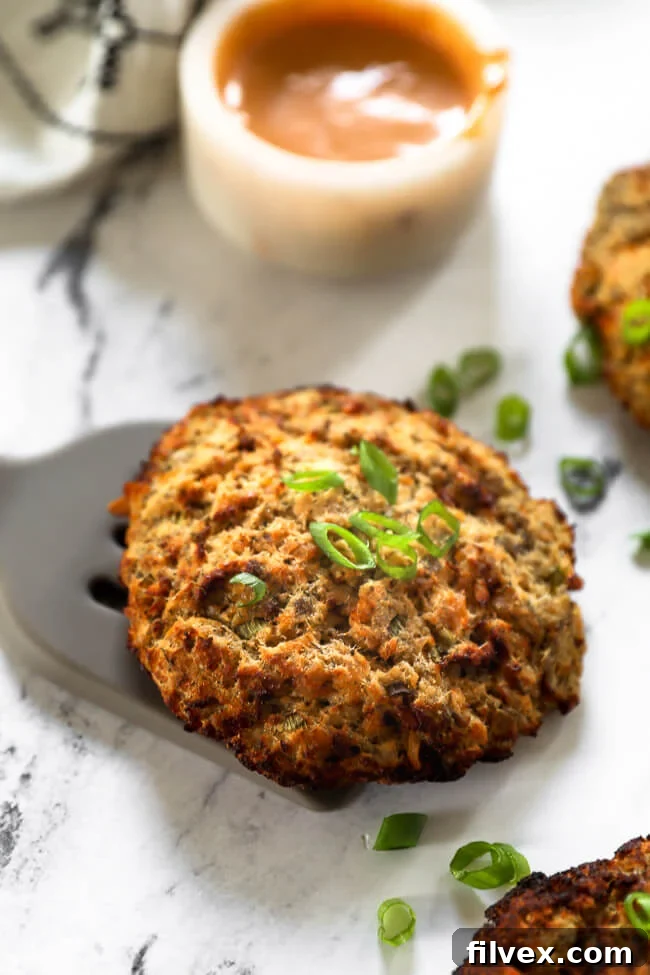 One cooked salmon patty on marble with a spatula underneath