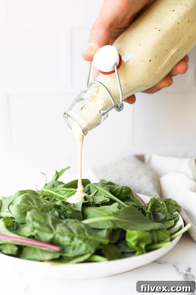 Image of pouring keto caesar dressing onto a plate of greens. The rich, creamy dressing gracefully drizzles over crisp, fresh lettuce, promising a delightful culinary experience.