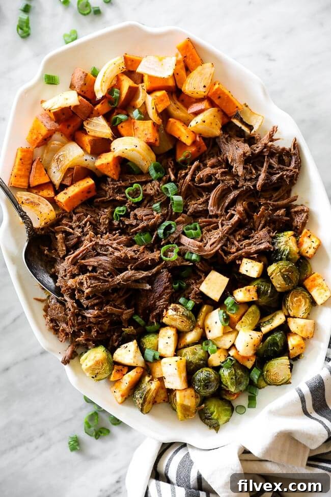 Overhead shot of a succulent slow cooker beef pot roast on a rustic platter, surrounded by a colorful array of roasted vegetables and a serving spoon on the side, ready to be enjoyed