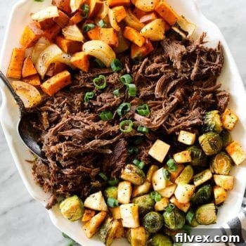 A vibrant close-up of the Slow Cooker Beef Pot Roast, showcasing the rich brown beef surrounded by colorful, tender vegetables like sweet potatoes and parsnips, all ready to be served.