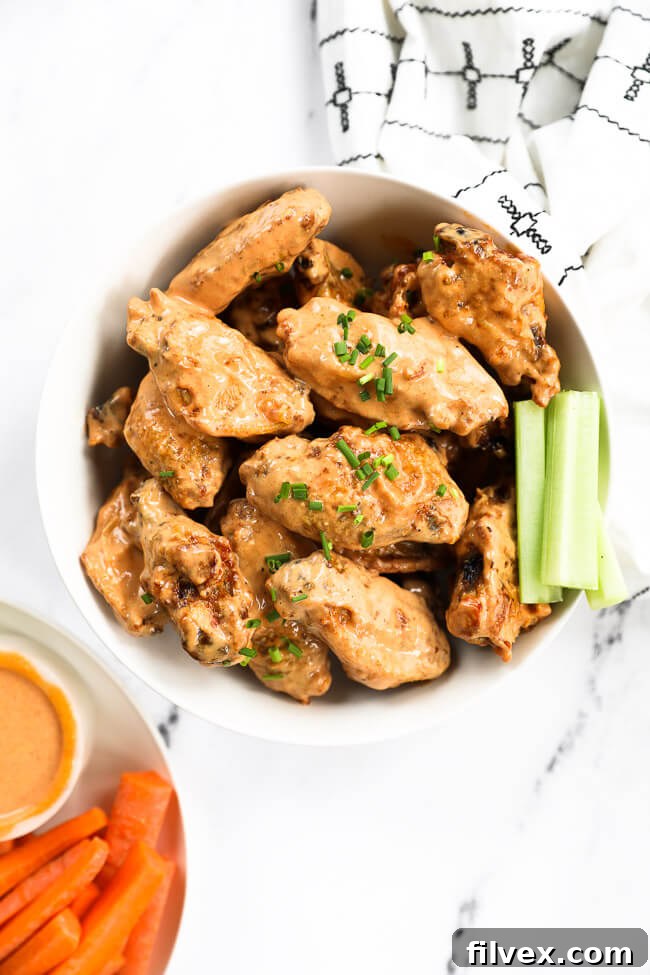 Bowl of crispy chicken wings generously tossed in creamy buffalo sauce, topped with fresh diced chives