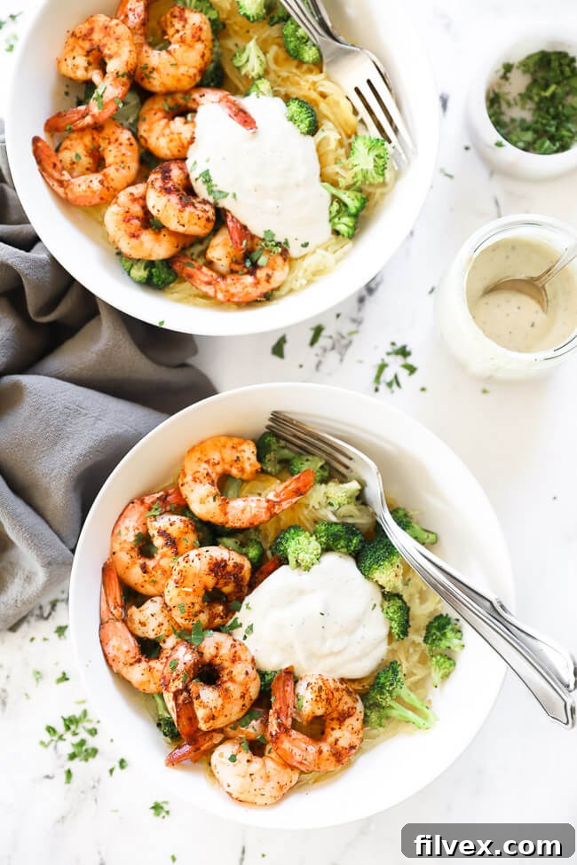 Two bowls of deconstructed spaghetti squash alfredo. Each bowl has spaghetti squash, shrimp, broccoli and a big pour of alfredo sauce. 