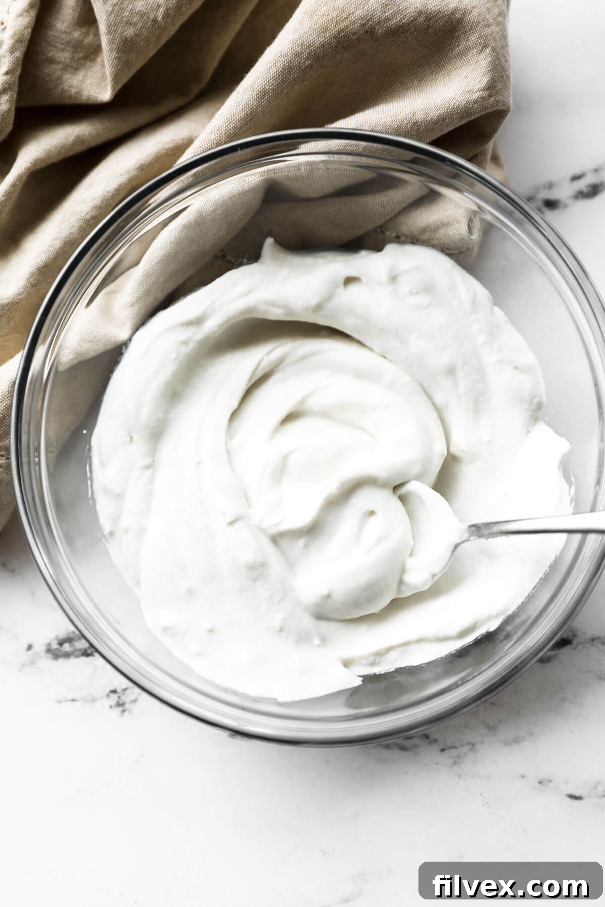 Dairy Free, Vegan whipped coconut cream in a bowl with a serving spoon.