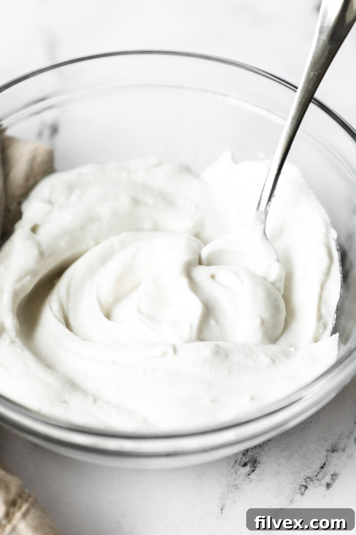 Angled shot of whipped coconut cream in a bowl with a spoon.