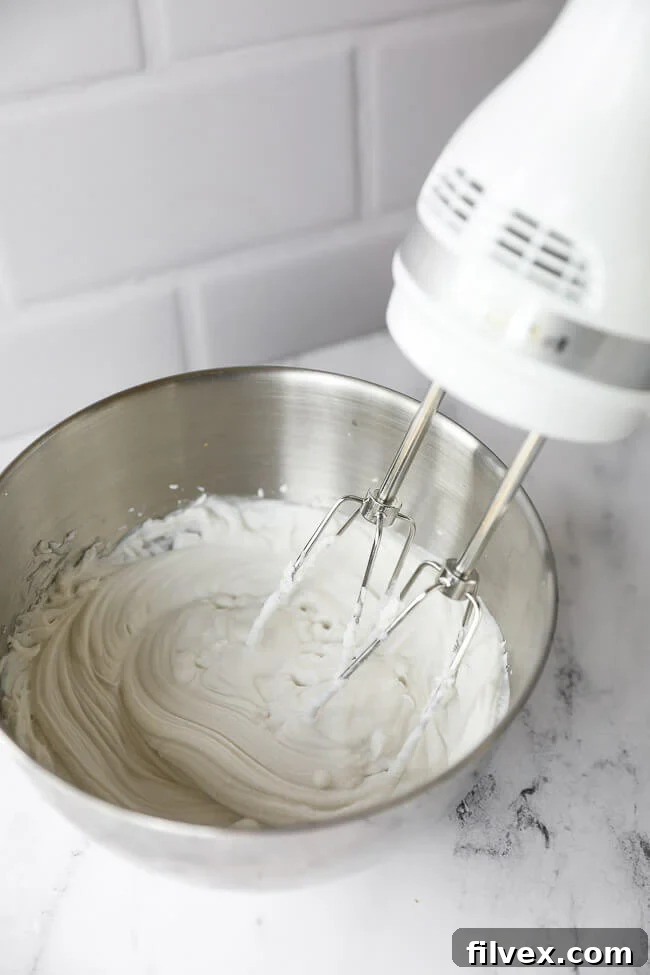 Whipping up coconut whipped cream in a metal bowl with a hand mixer. 
