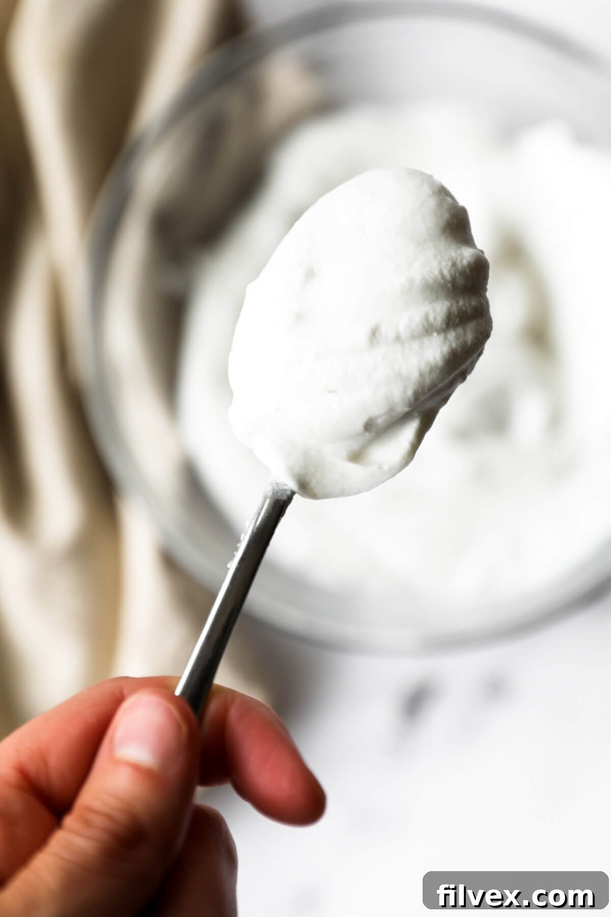Close up image of holding a spoonful of coconut cream whipped cream. 