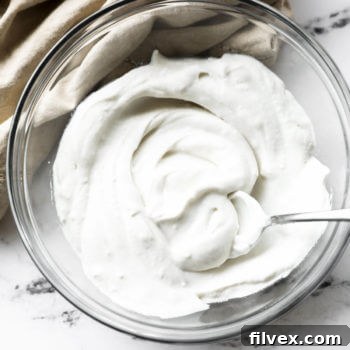 Dairy Free, Vegan whipped coconut cream in a bowl with a serving spoon.