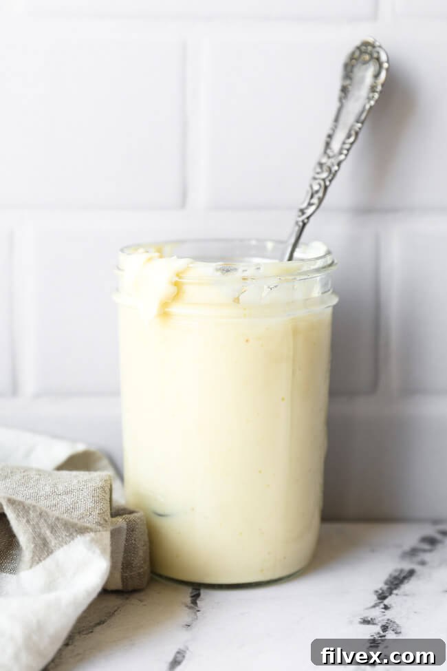 Jar of creamy homemade Keto and Whole30 avocado oil mayo with a spoon, ready to be served and enjoyed