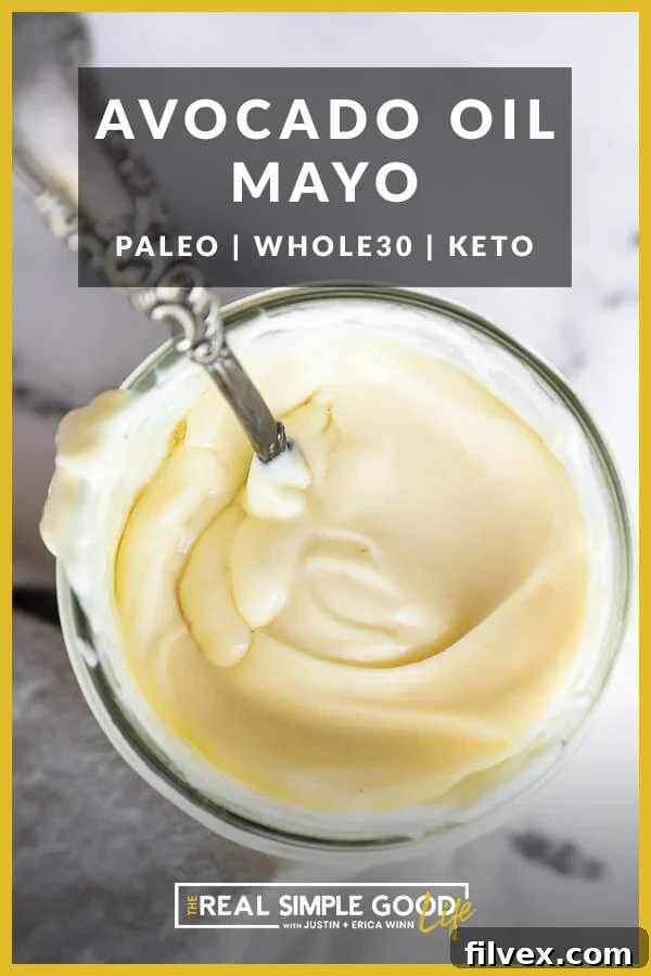 Overhead shot of creamy homemade avocado oil mayo in a elegant glass jar with a small spoon, showcasing its perfect, luscious texture
