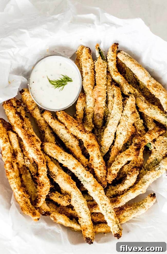Breaded air fryer green beans on a plate with ranch sauce