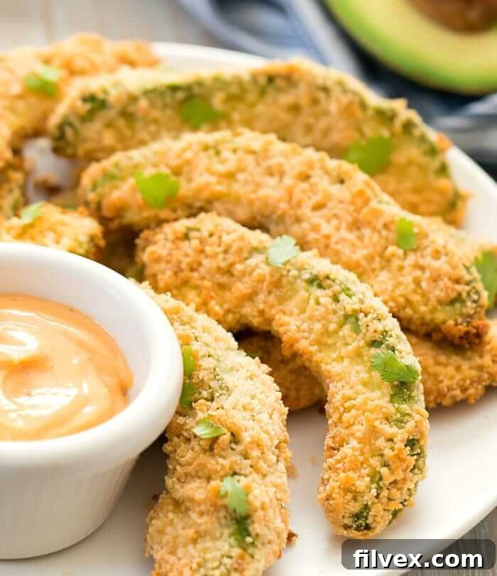 Breaded avocado wedges on a plate with dipping sauce