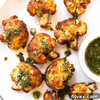 Crispy air fryer cauliflower on a white plate with green sauce on top and on the side