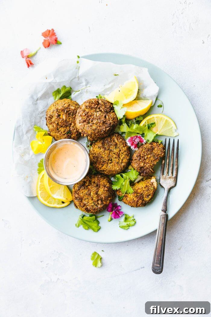 A plate of sweet potato cauliflower patties with fork and lemon wedges