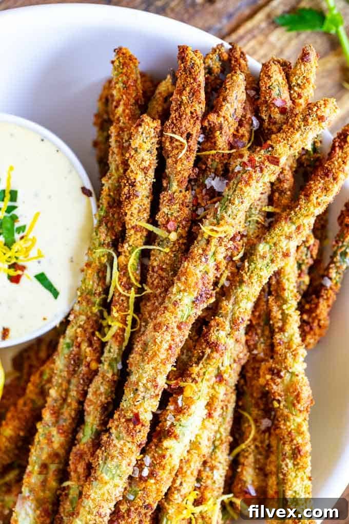 A plate of cheesy asparagus fries with sauce