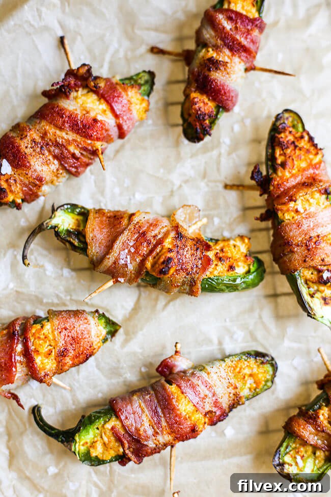 Stuffed jalapeno peppers wrapped in bacon on parchment paper