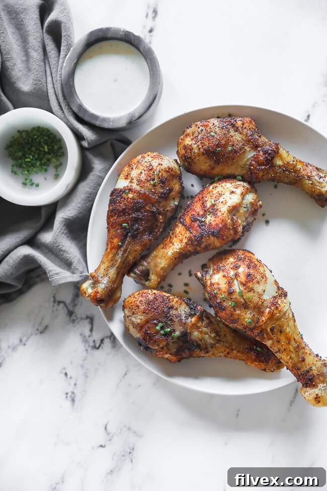 Air fryer chicken drumsticks on a plate with chives sprinkled on top