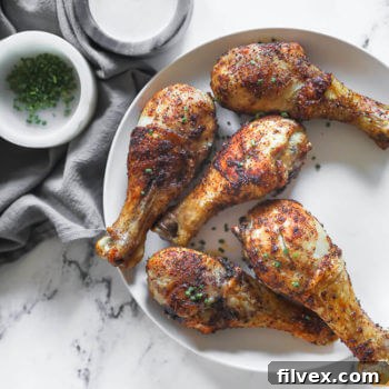 Air fryer chicken drumsticks on a plate with chives sprinkled on top