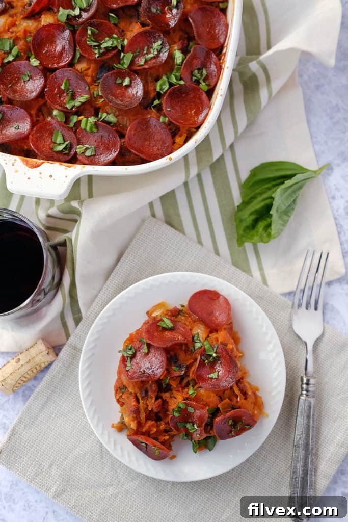 An enticing shot of a serving of Paleo Lasagna on a plate, garnished with fresh basil. The image highlights the rich red sauce, pieces of savory pepperoni, and the tender, 'noodle-like' strands of spaghetti squash, emphasizing its delicious and healthy nature.