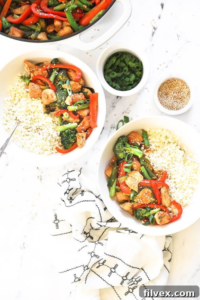 Overhead image of teriyaki chicken stir fry served up in two bowls with cauliflower rice. 