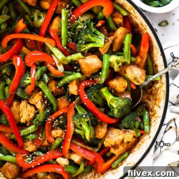 Close up overhead image of healthy teriyaki chicken in a skillet with a serving spoon scooped in.