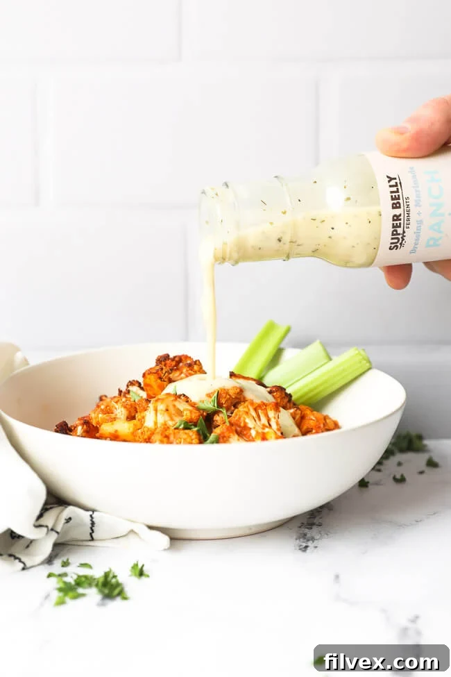 Air fryer buffalo cauliflower in a bowl with ranch being poured on top