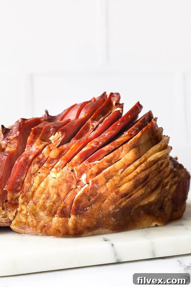 Close up straight on shot of whole ham with a thick spiral slice on a marble board