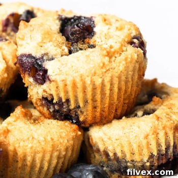 Close-up of a stack of gluten-free blueberry muffins, showing their golden tops and tender crumb.