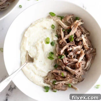 Instant pot pork shoulder served over mashed cauliflower in a bowl.