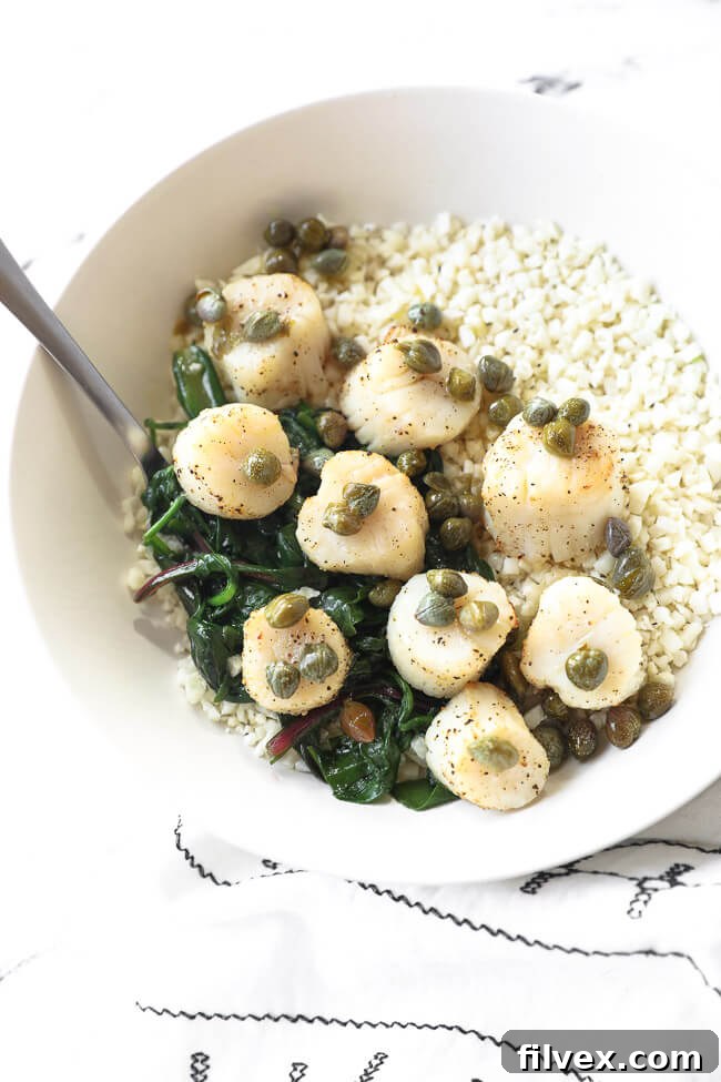 Cooked scallops in a bowl over cauliflower rice and wilted greens