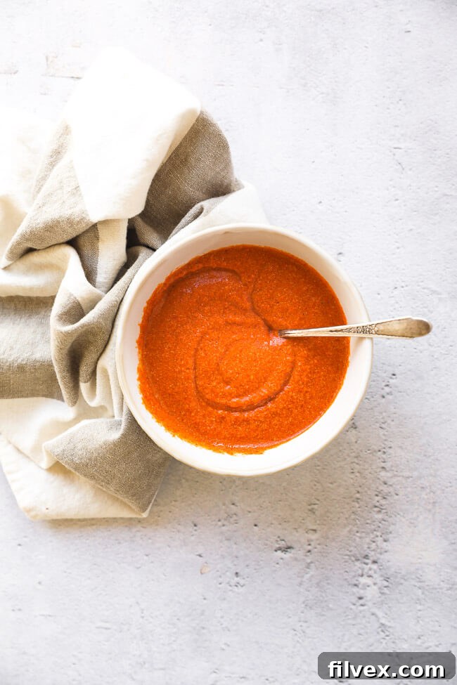 Overhead shot of ramekin full of buffalo sauce with spoon in ramekin, ready to be served or used in a recipe.