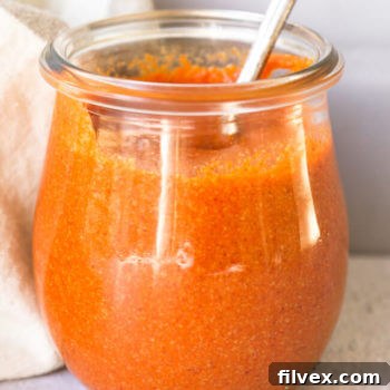 Homemade keto buffalo sauce in a small jar with spoon coming out, representing the finished recipe.