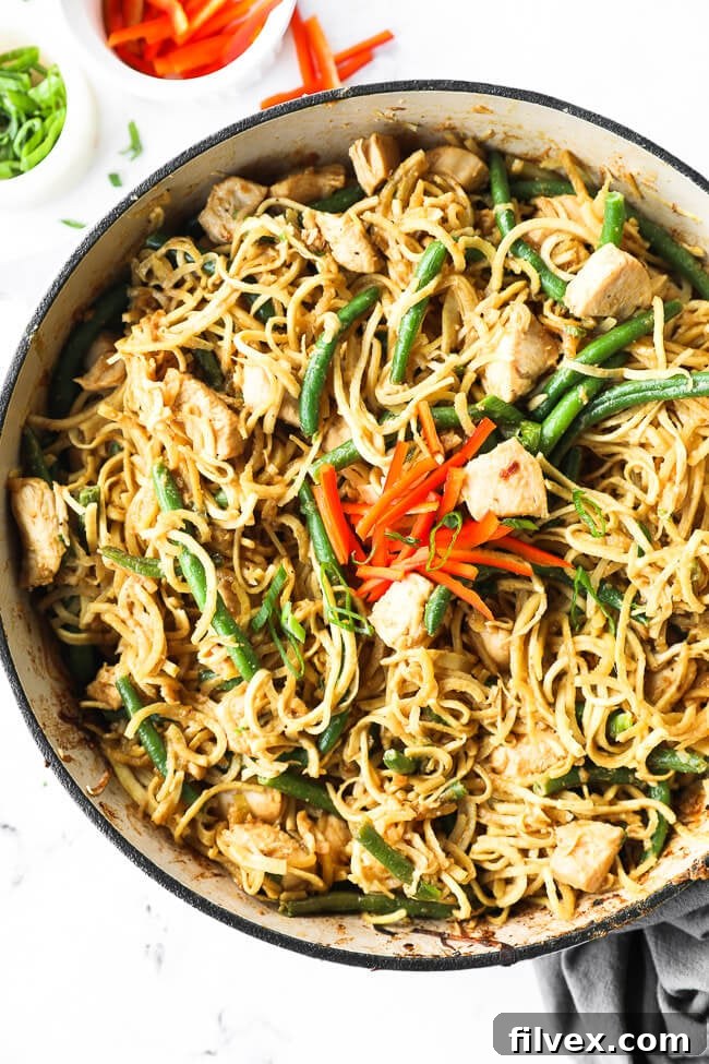 Large skillet filled with peanut butter chicken and spiralized sweet potato noodles. 