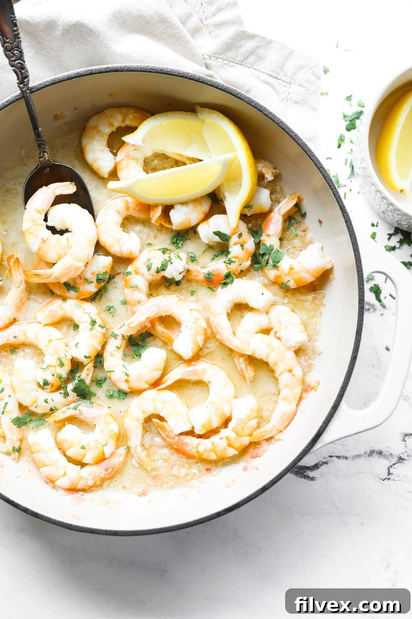 Overhead close up of skillet full of garlic butter shrimp sprinkled with chopped cilantro.