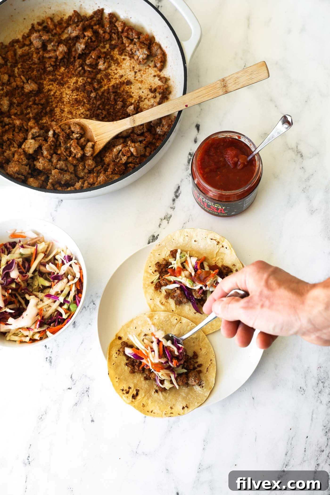 A beautifully assembled ground pork taco, showcasing the seasoned meat generously topped with the fresh, vibrant coleslaw and creamy avocado, nestled in a soft tortilla.