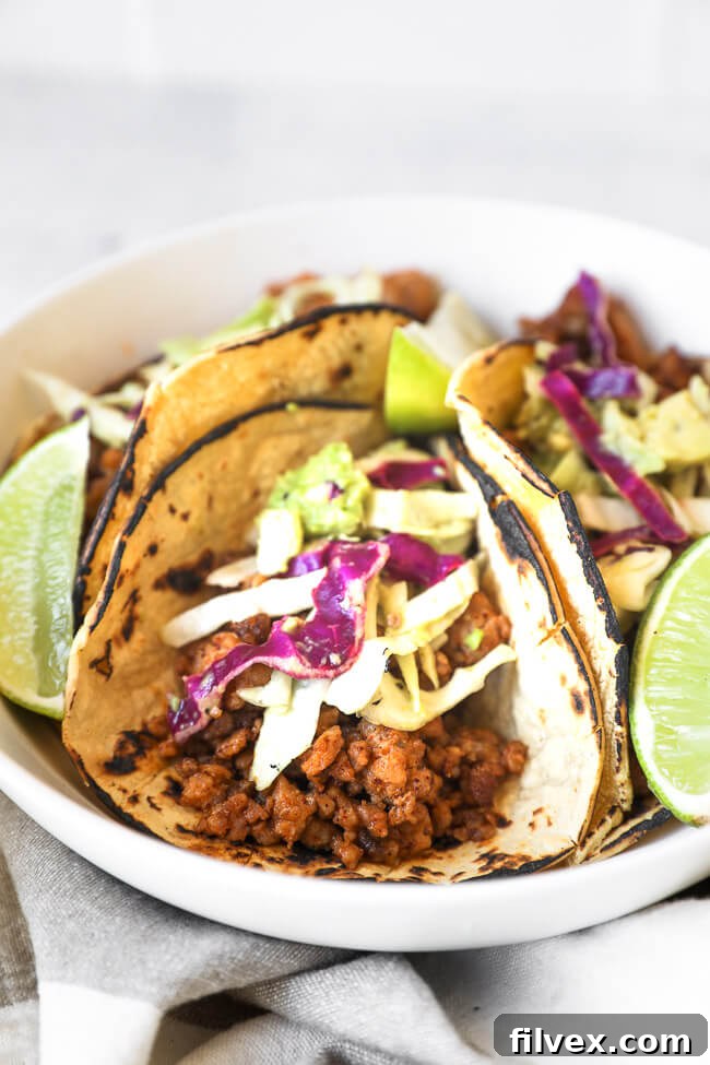 Close-up, straight-on view of a single ground pork taco, beautifully topped with fresh cabbage and avocado slaw, offering a tantalizing glimpse of its texture and vibrant colors.