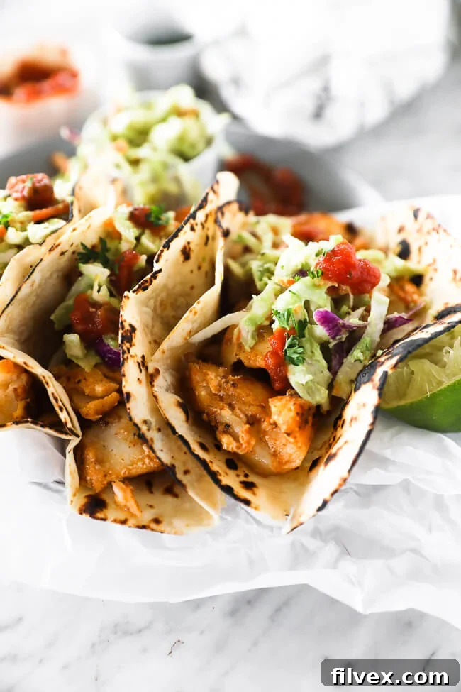 Vertical angled image close up image of fish tacos on a plate. 
