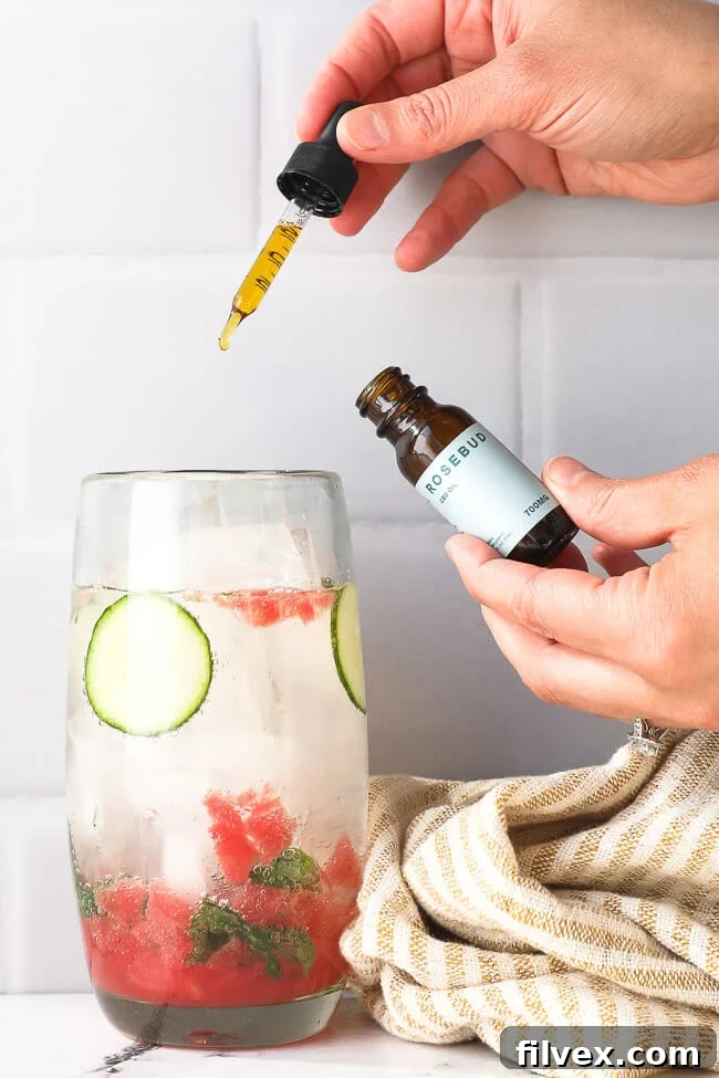 Image of using a dropper of Rosebud CBD to add CBD to a watermelon cucumber mojito mocktail. 