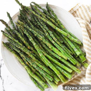 Air fryer asparagus served on a plate with a side of dipping sauce.