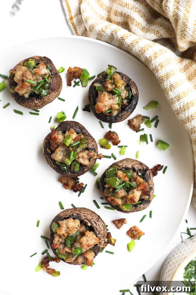 A plate of freshly baked sausage stuffed mushrooms on a rustic wooden surface.