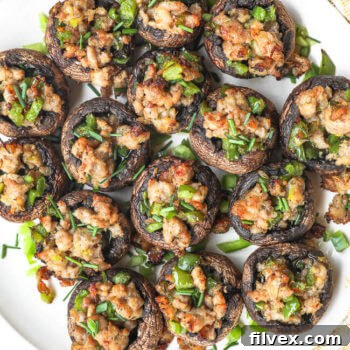 Overhead image of a plate full of sausage stuffed mushrooms.