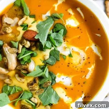 Close up overhead image of curried butternut squash soup, garnished with herbs.