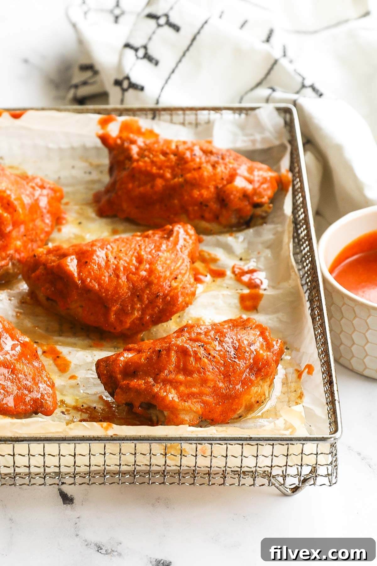Buffalo chicken thighs cooking in an air fryer