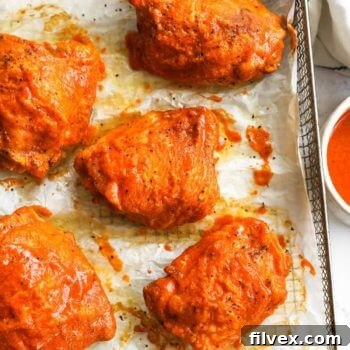 Overhead image of air fryer chicken thighs with buffalo sauce