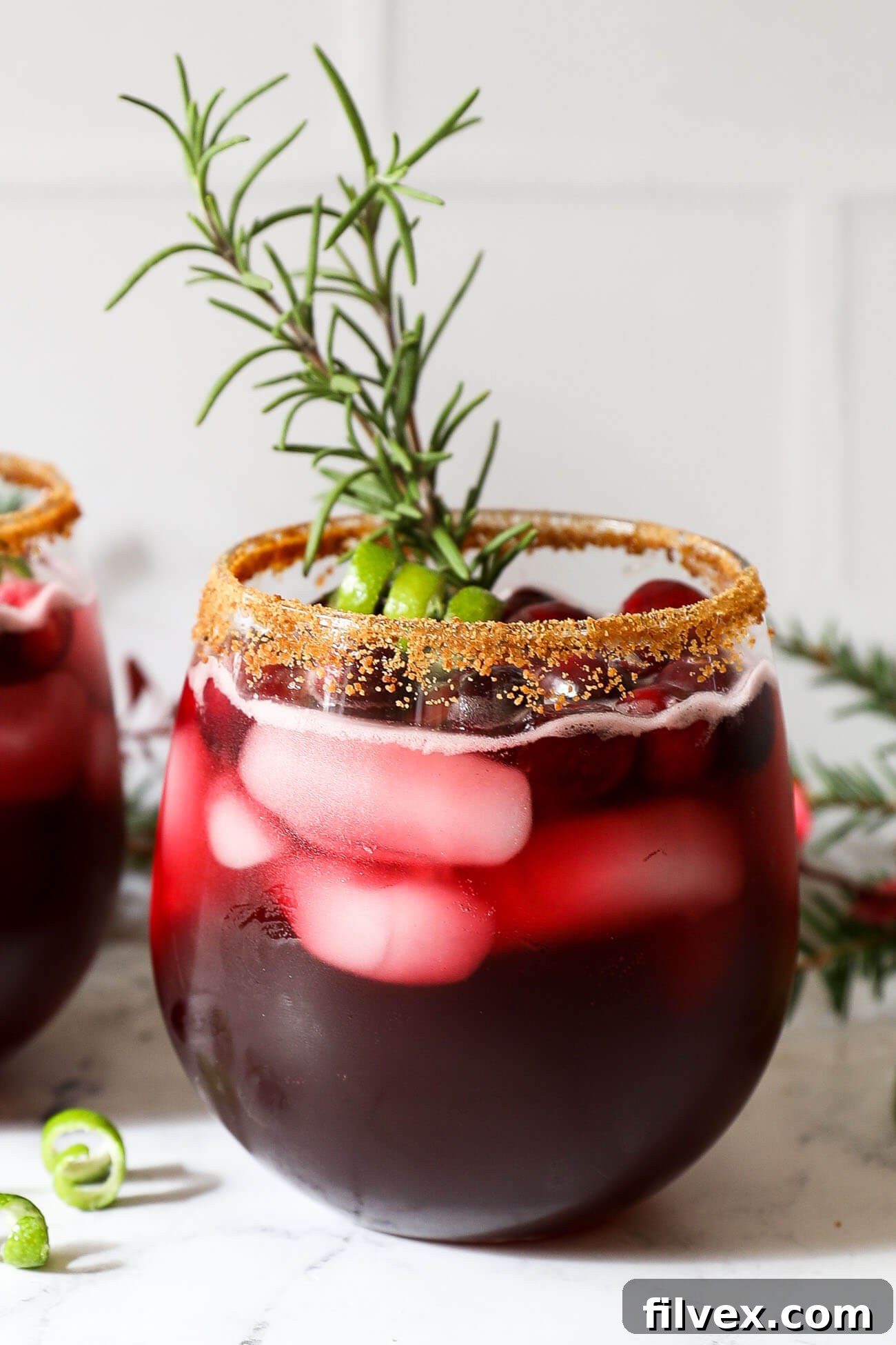 A close-up of a festive red cocktail with ice and a garnish, showcasing its vibrant color and inviting appeal.