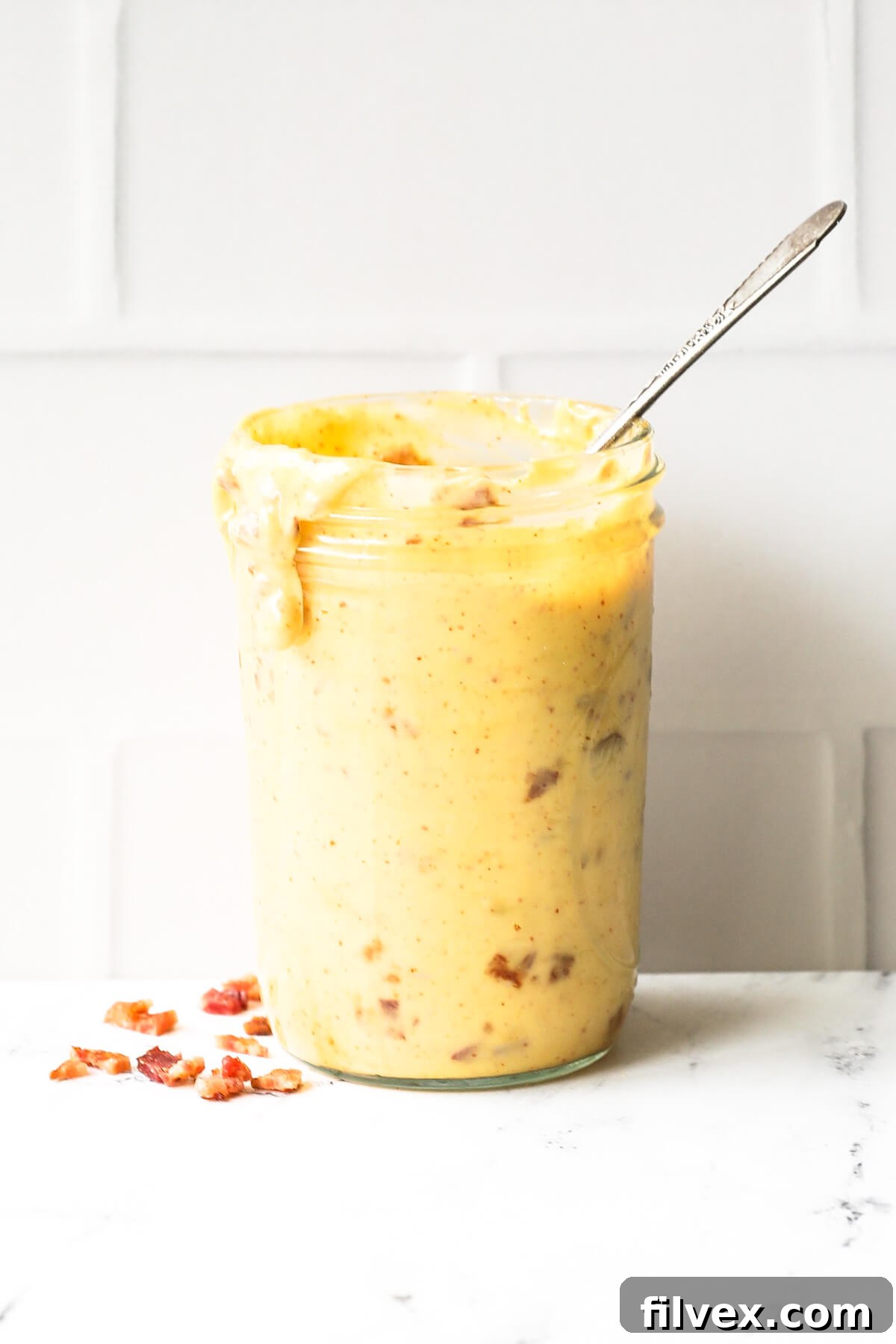 Close-up of freshly made bacon aioli in a ramekin with crispy bacon bits